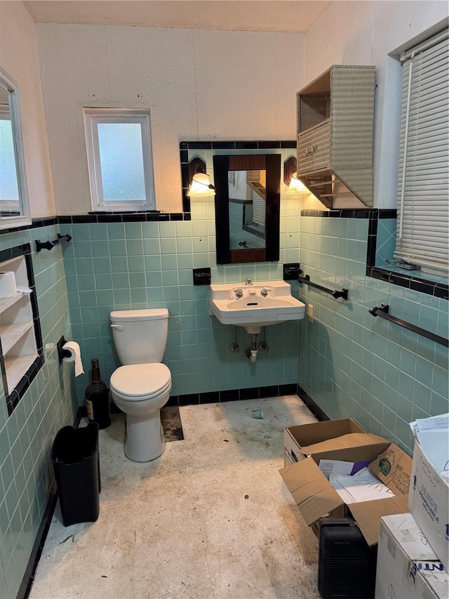 bathroom featuring toilet, a wealth of natural light, tile walls, and a sink