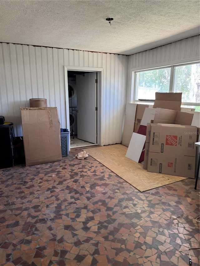 interior space featuring a textured ceiling and stacked washing maching and dryer