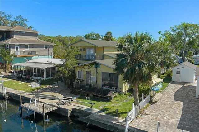 rear view of property with a yard, a water view, fence, and a sunroom