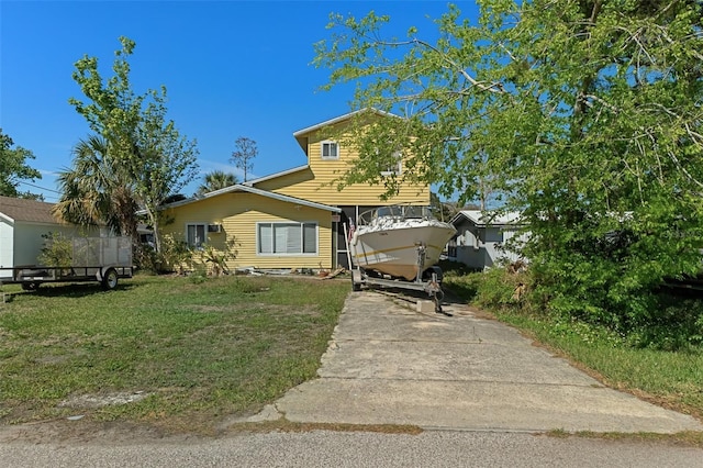 view of front of home featuring concrete driveway and a front lawn