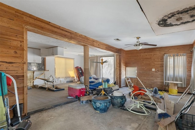 interior space with a ceiling fan, visible vents, and wooden walls