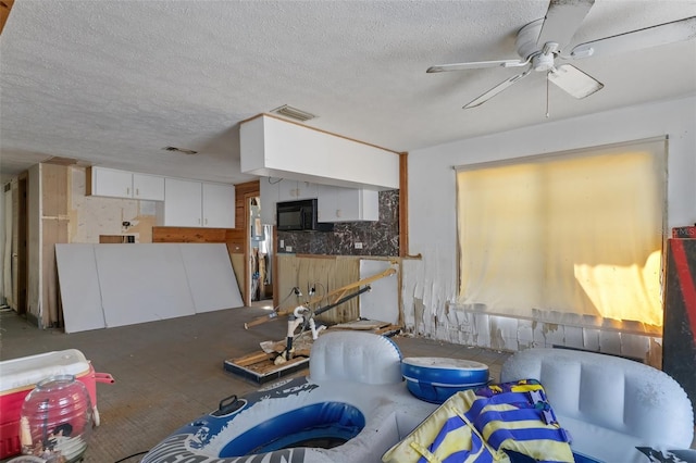 living room with a ceiling fan, visible vents, and a textured ceiling