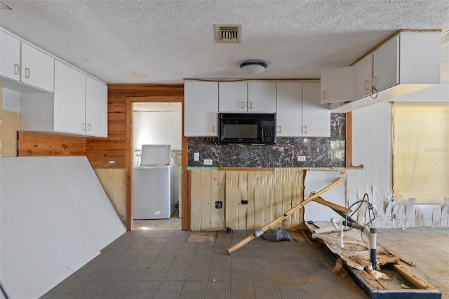 kitchen featuring washer / clothes dryer, visible vents, decorative backsplash, white cabinets, and black microwave