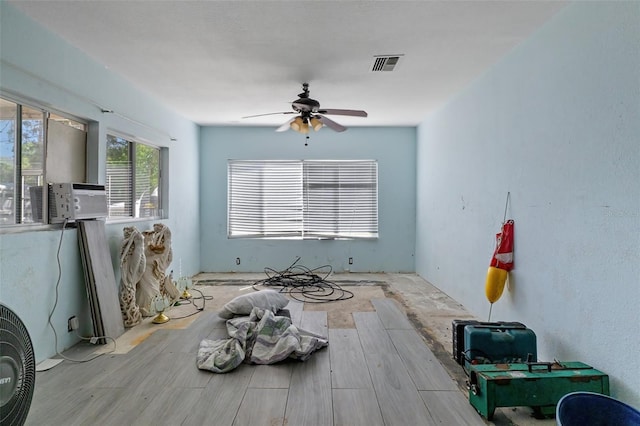 empty room featuring cooling unit, wood finished floors, visible vents, and a ceiling fan