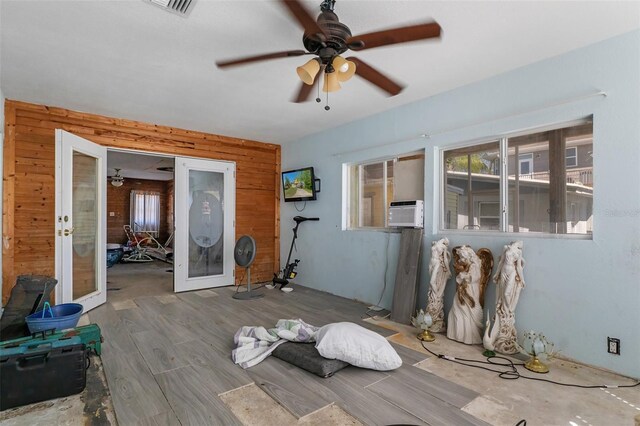 empty room featuring ceiling fan, plenty of natural light, wood walls, and wood finished floors