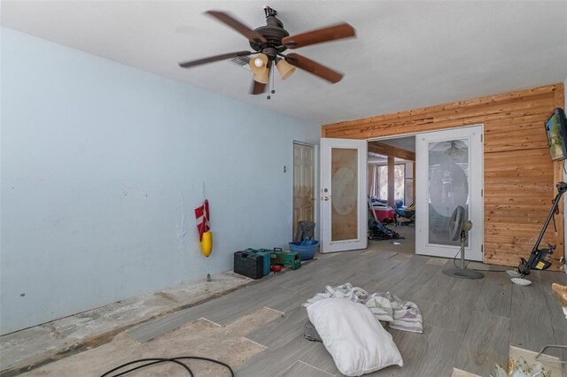 unfurnished bedroom featuring wood walls, a ceiling fan, and wood finished floors