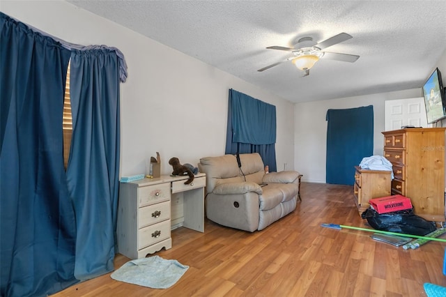 sitting room featuring light wood-type flooring, ceiling fan, and a textured ceiling