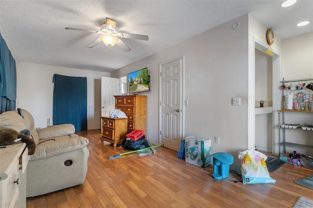 interior space with a textured ceiling, light wood-type flooring, and a ceiling fan