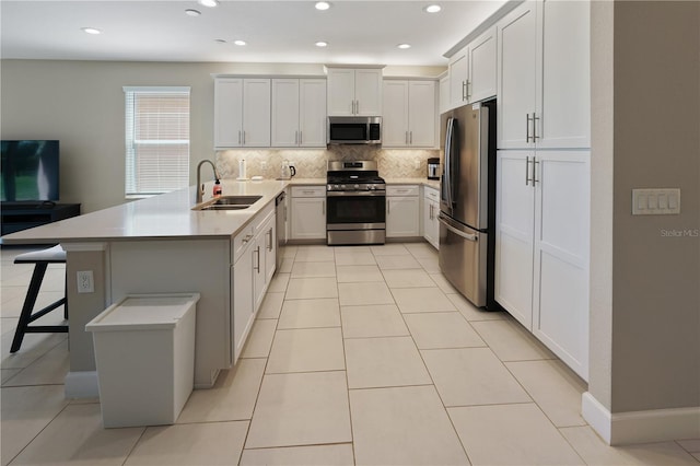 kitchen featuring stainless steel appliances, tasteful backsplash, light tile patterned flooring, a sink, and a peninsula