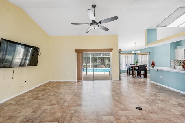 interior space featuring lofted ceiling, baseboards, and ceiling fan with notable chandelier