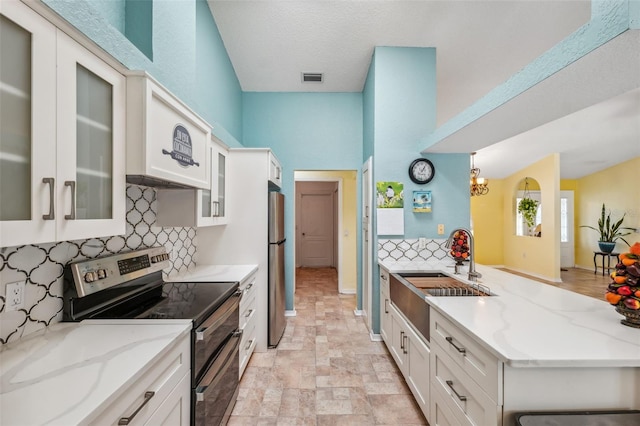 kitchen with stainless steel appliances, a peninsula, a sink, visible vents, and white cabinetry