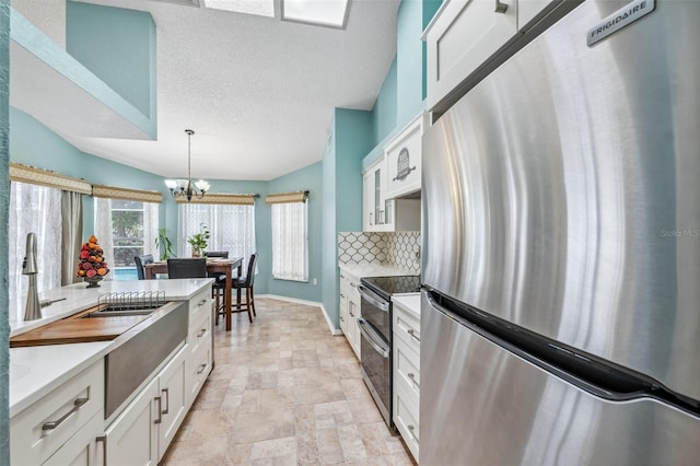 kitchen with pendant lighting, stainless steel appliances, light countertops, decorative backsplash, and white cabinets