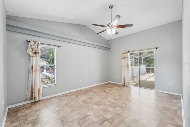 empty room featuring lofted ceiling, plenty of natural light, baseboards, and a ceiling fan