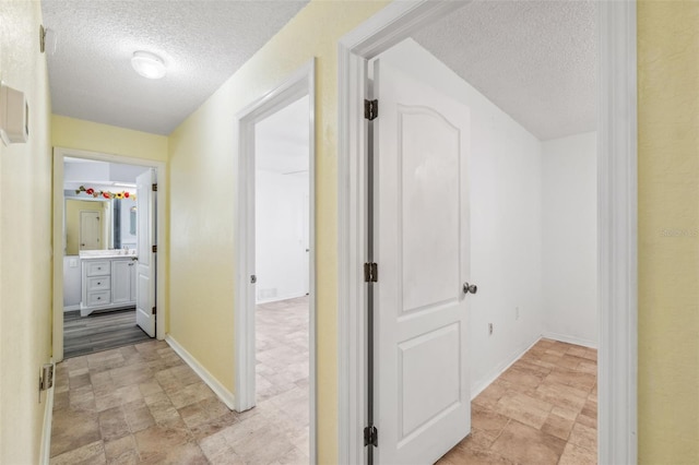 hall with a textured ceiling and baseboards