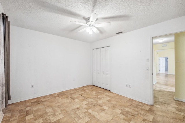 unfurnished bedroom with a textured ceiling, a ceiling fan, visible vents, baseboards, and a closet