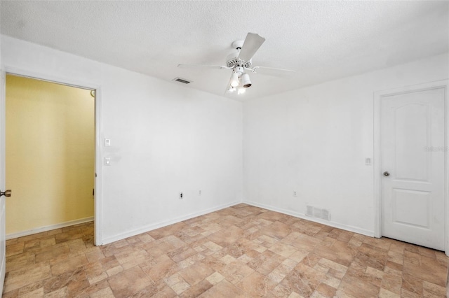 spare room with ceiling fan, a textured ceiling, visible vents, and baseboards