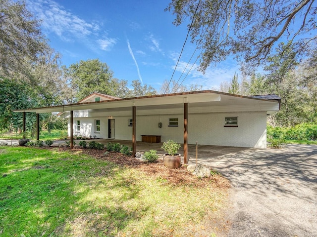 view of front of home featuring a carport, a front yard, and driveway