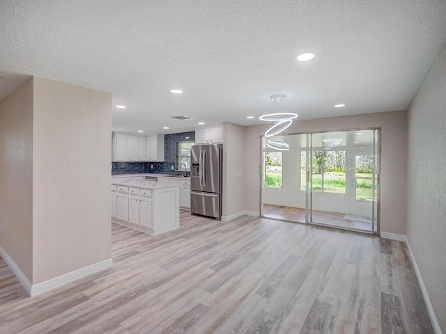 kitchen featuring light countertops, white cabinets, light wood-style floors, and stainless steel fridge