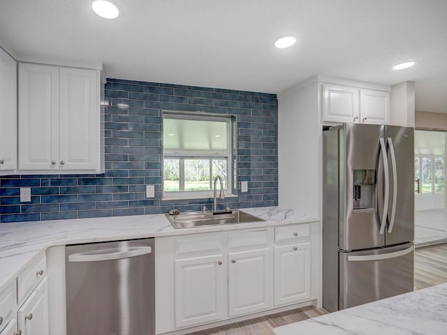 kitchen featuring a sink, stainless steel appliances, and light stone countertops