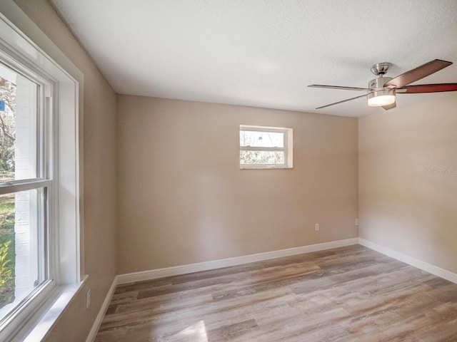 spare room with light wood-style flooring, a textured ceiling, baseboards, and ceiling fan