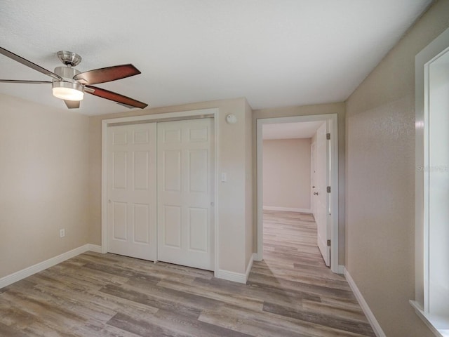 unfurnished bedroom with ceiling fan, a closet, baseboards, and wood finished floors