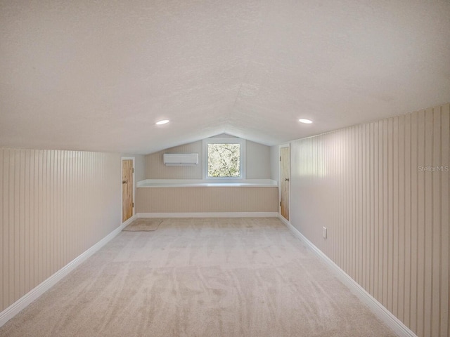 bonus room with baseboards, light colored carpet, lofted ceiling, a textured ceiling, and a wall mounted AC