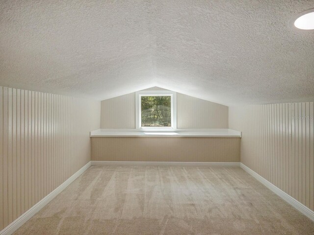 bonus room featuring carpet flooring, a textured ceiling, baseboards, and vaulted ceiling