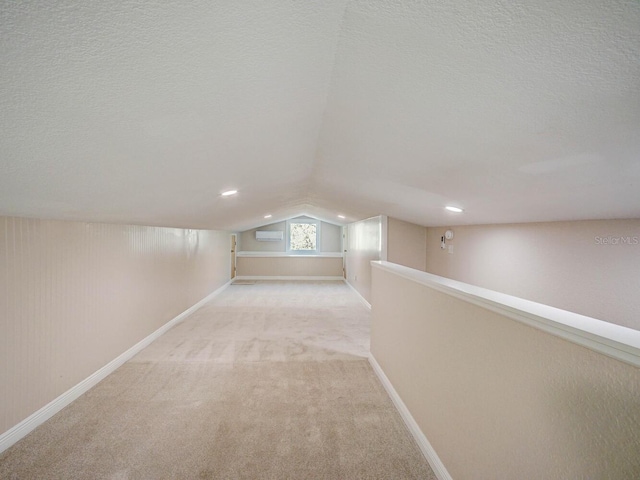 interior space featuring vaulted ceiling, light colored carpet, baseboards, and a textured ceiling