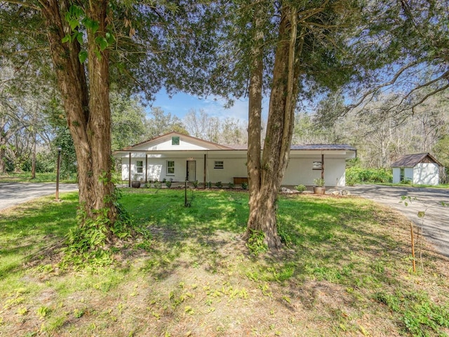 ranch-style house featuring a front lawn, covered porch, and aphalt driveway