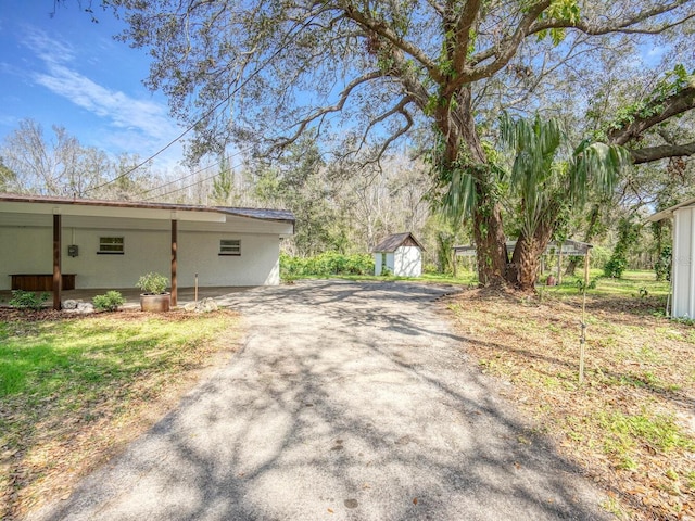 view of property exterior with a storage unit, an outbuilding, and driveway