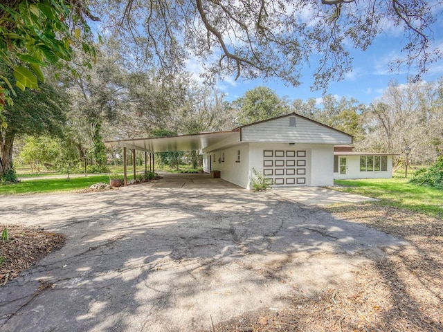 view of property exterior with stucco siding, an attached carport, an attached garage, and driveway