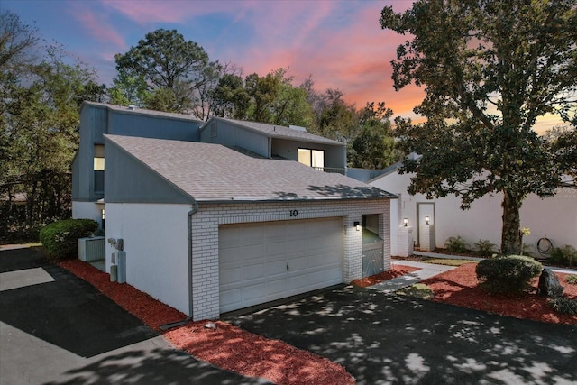 view of front of home featuring a garage, brick siding, roof with shingles, and aphalt driveway