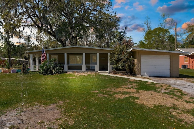 view of front of property with a front lawn, cooling unit, covered porch, and driveway