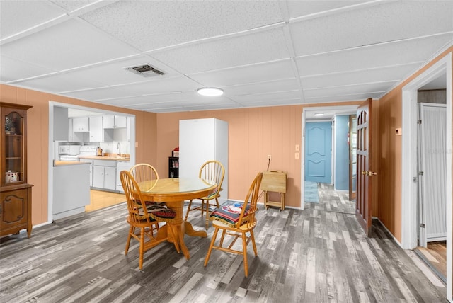 dining room featuring light wood-type flooring, visible vents, and a drop ceiling