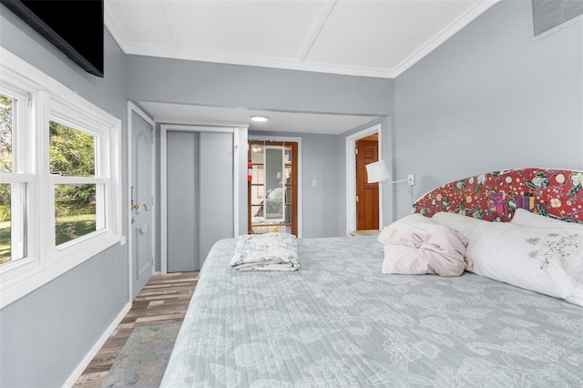 bedroom featuring visible vents, baseboards, wood finished floors, and crown molding