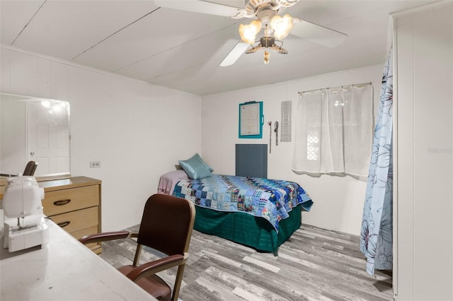 bedroom with crown molding, wood finished floors, and ceiling fan