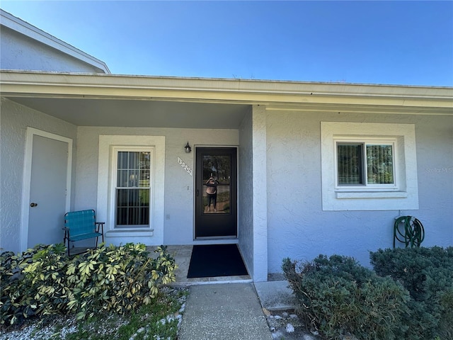 entrance to property featuring a porch and stucco siding