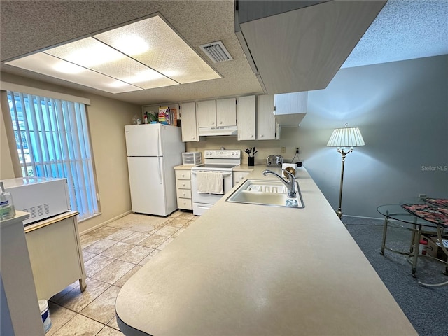 kitchen featuring white appliances, visible vents, light countertops, under cabinet range hood, and a sink