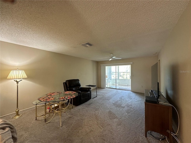 sitting room with a ceiling fan, carpet, visible vents, and a textured ceiling