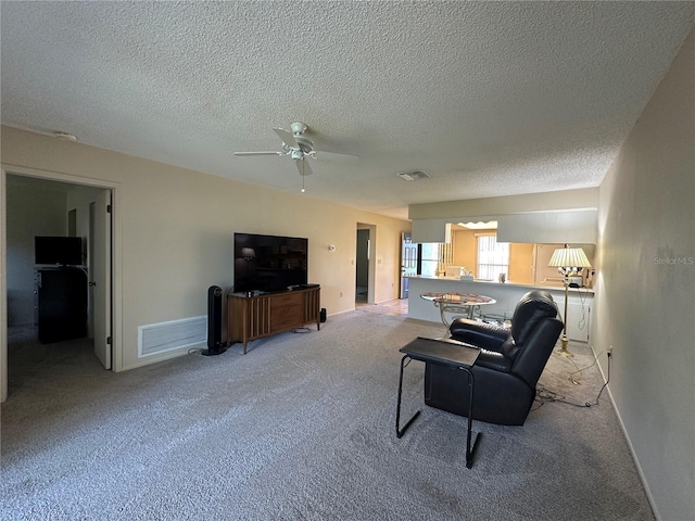 living room featuring a ceiling fan, visible vents, and light colored carpet