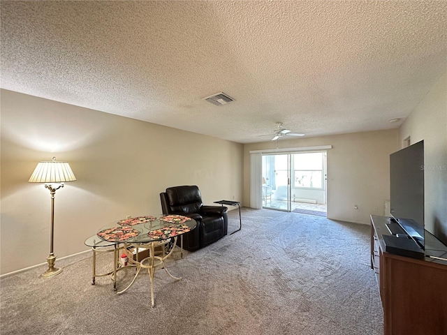 sitting room with ceiling fan, a textured ceiling, carpet flooring, and visible vents