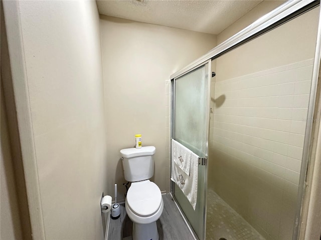 full bath featuring a textured ceiling, a stall shower, and toilet