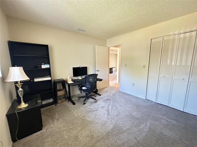 carpeted office featuring visible vents and a textured ceiling