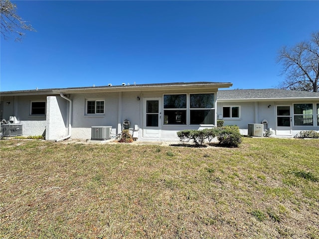 back of property with a lawn, cooling unit, and stucco siding