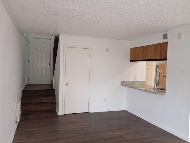 kitchen featuring freestanding refrigerator, brown cabinets, dark wood finished floors, and visible vents