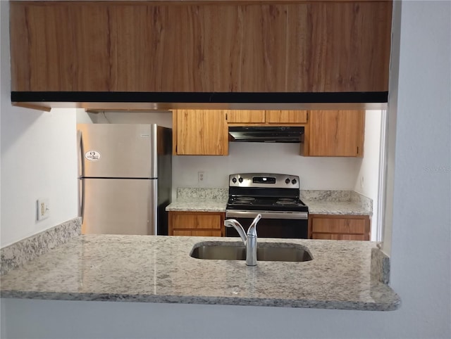 kitchen with brown cabinets, appliances with stainless steel finishes, a sink, and under cabinet range hood