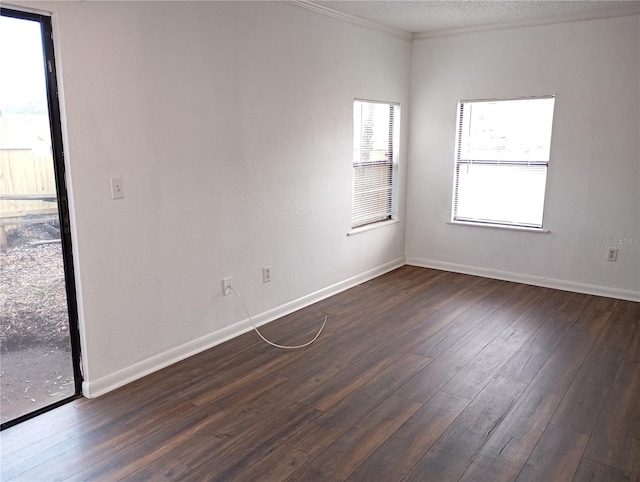 empty room featuring a textured ceiling, baseboards, dark wood-type flooring, and ornamental molding