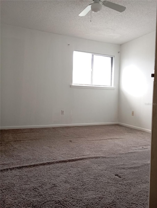 spare room featuring carpet floors, ceiling fan, a textured ceiling, and baseboards