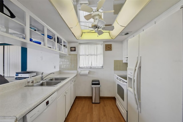 kitchen with white appliances, decorative backsplash, a sink, and light wood-style floors