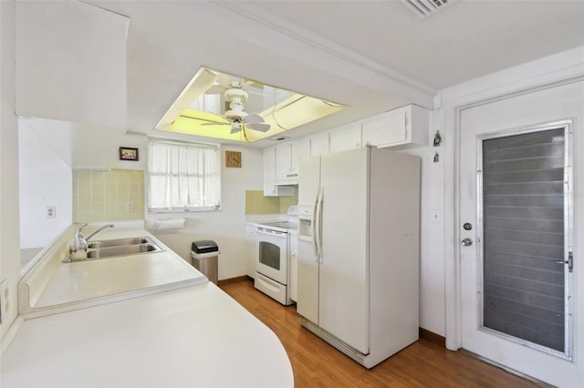 kitchen with light countertops, a sink, light wood-type flooring, white appliances, and under cabinet range hood